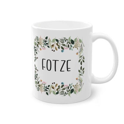 a white coffee mug with a floral frame on it